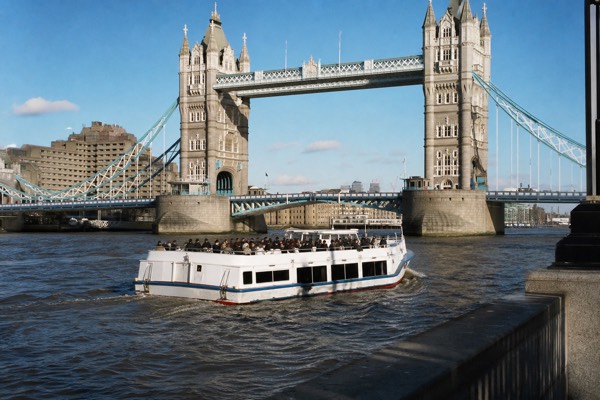Sightseeing cruise boat passing under Tower Bridge on the Thames in daylight