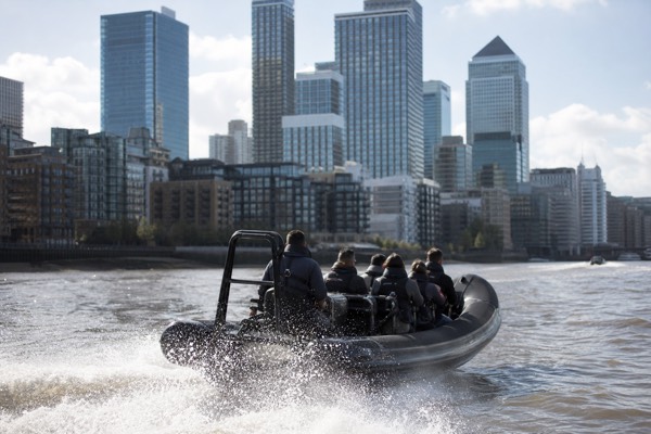 Rigid inflatable speedboat cutting across the Thames at speed near Canary Wharf
