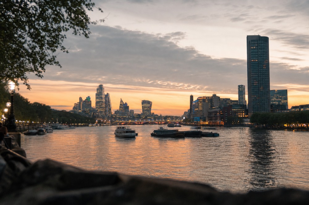 Warm low sun on riverside buildings with the water carrying orange reflections and the first lights showing on a bridge