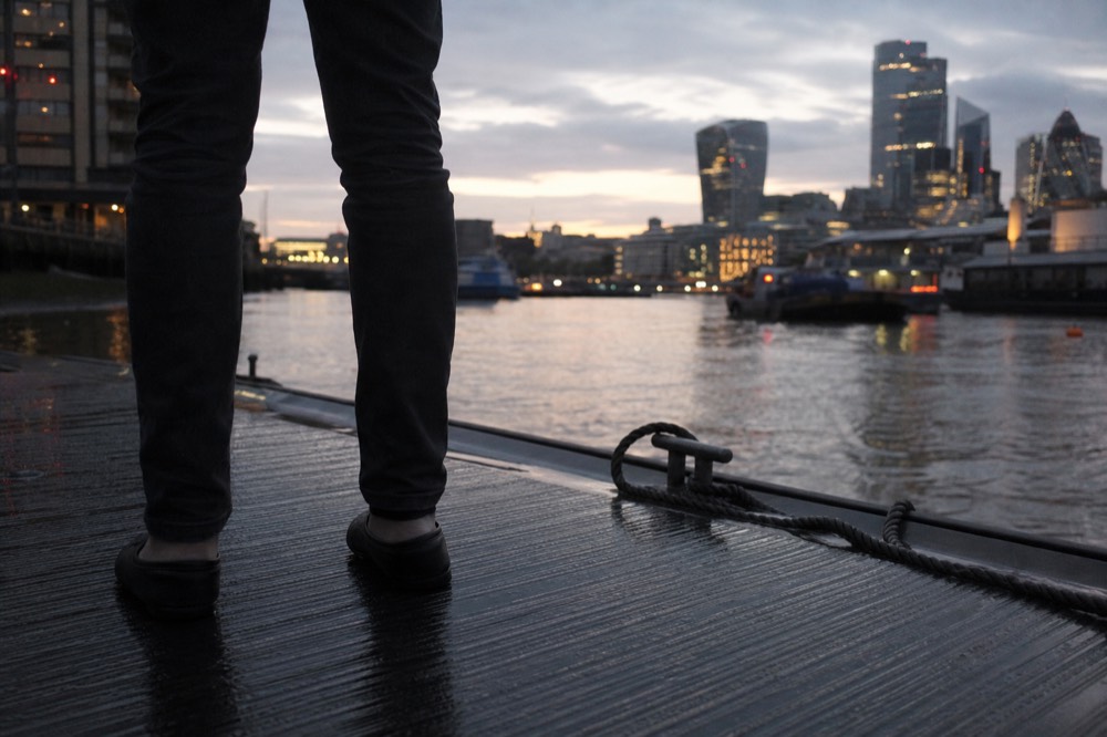 Flat leather shoes standing on the wet ridged decking of a floating pontoon, mooring rope and dark water at the edge