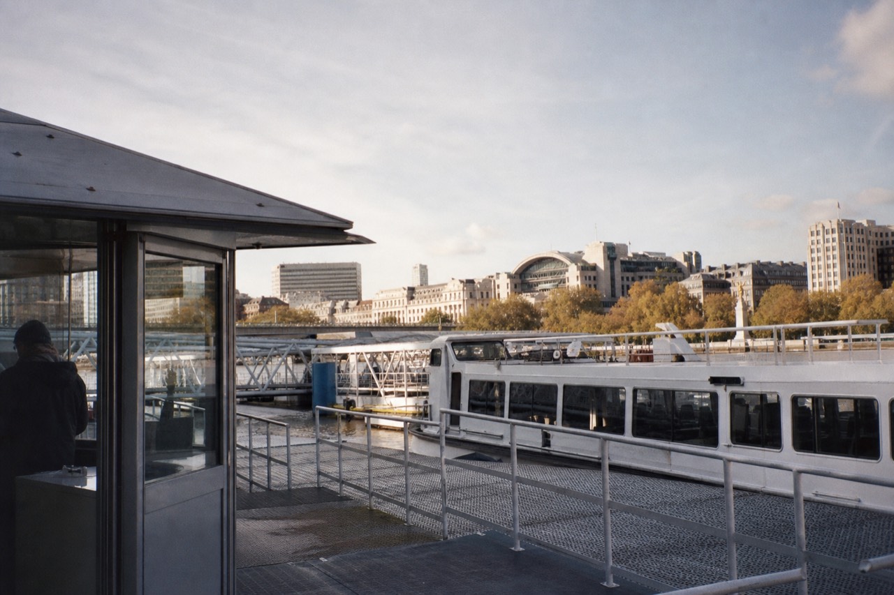 Passengers on the open deck of a Thames sightseeing boat in daylight