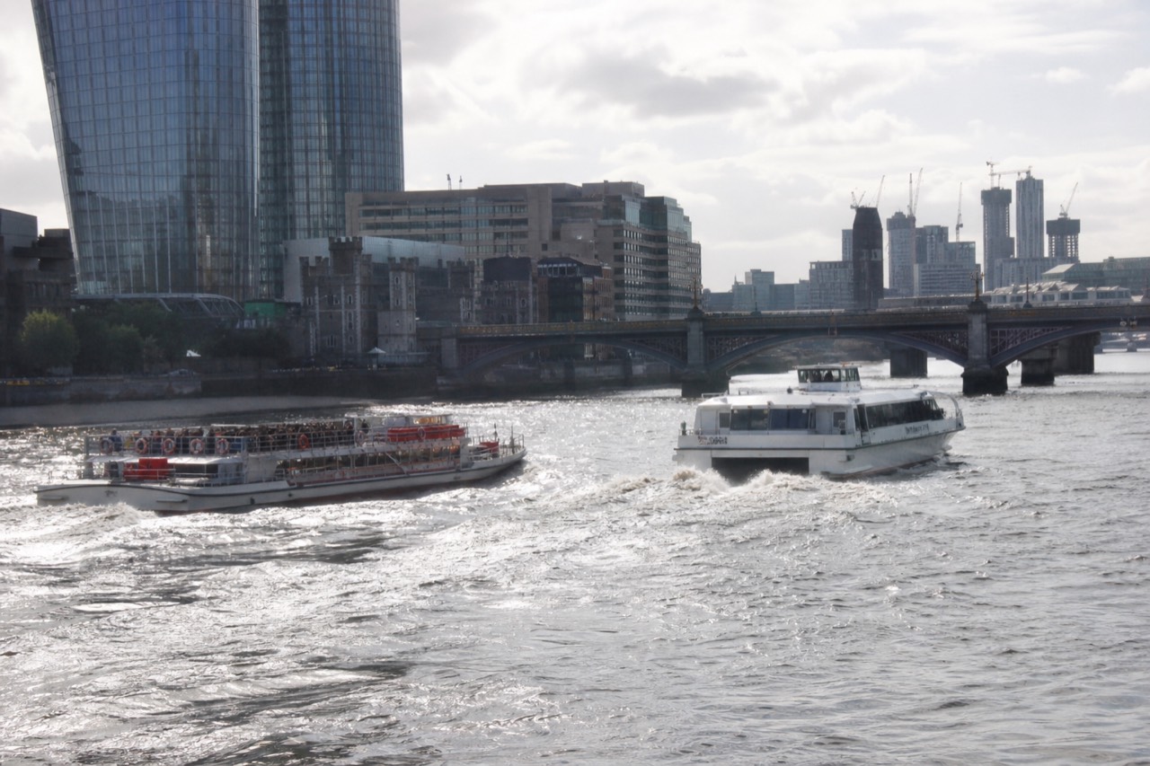 Fast river catamaran passing a slower sightseeing boat on the Thames